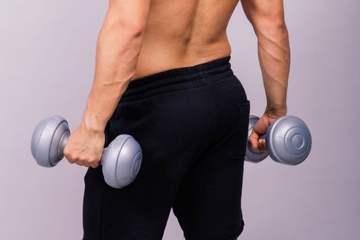 Shirtless bodybuilder showing his great body and holding dumbells.