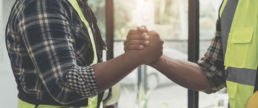 construction worker team hands shaking after consultation meeting to greeting start up plan new project contract in office center at construction site, teamwork, partnership and contractor concept..