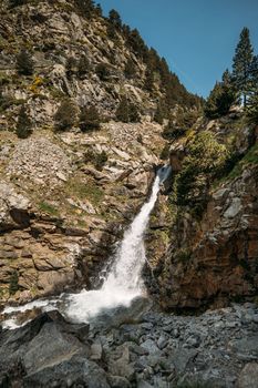 Small mountain river in the valley of Vall de Nuria Spain is gaining strength at the top of the Pyrenees. The channel of clear cold water moves down with unrestrained pressure along a gentle slope