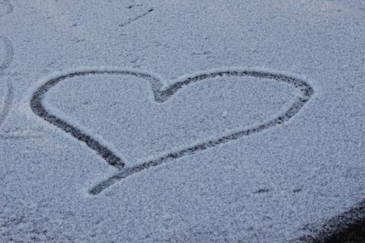heart is drawn in snowy glade. background for decoration for holiday of Valentine's Day. Cold heart, love. white snow in winter, romance. Love symbol in snow. space for text. High quality photo