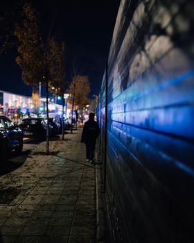 Emergency light reflections at night in wall. Boy walking in darkness towards mall with emergency lights.