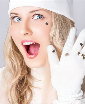 Happy holidays, Merry Christmas, and a woman wearing a white hat and gloves. Female model celebrating, looking beautiful, and wearing the latest fashions. Surprised funny blonde girl laughing and smiling while enjoying Christmas, New Year, and winter holidays.