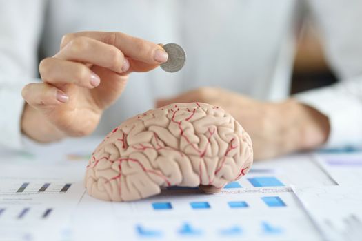 Businesswoman put coin into human brain model. Money investment in education concept