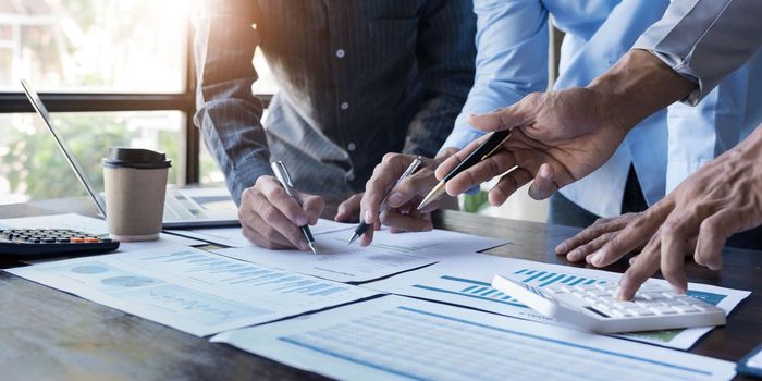 Business People Meeting using laptop computer,calculator,notebook,stock market chart paper for analysis Plans to improve quality next month. Conference Discussion Corporate Concept...