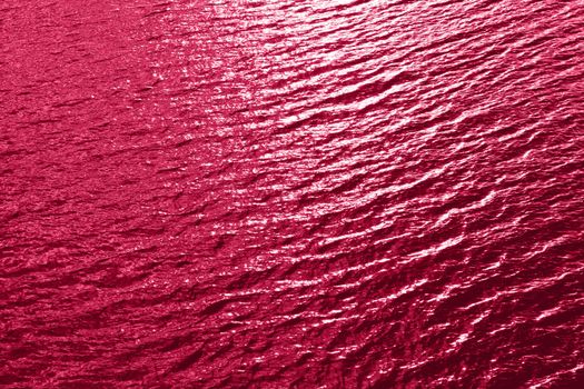 Viva Magenta toned sea water texture. Pool water with sun reflections. Trendy colour 2023 year. High quality photo