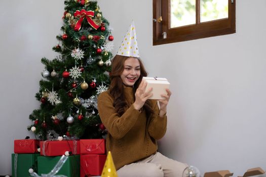 Merry Christmas and Happy Holidays Young woman with a beautiful face in a yellow shirt shows joy with gift boxes in a house