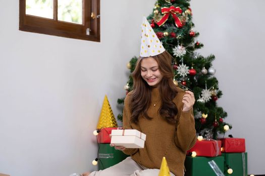 Merry Christmas and Happy Holidays Young woman with a beautiful face in a yellow shirt shows joy with gift boxes in a house