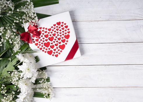 Valentine's day gift, red heart praline box and flower bouquet on white wooden table. High quality photo