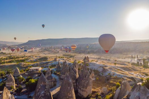 Colorful hot air balloons flying over at fairy chimneys valley in Nevsehir, Goreme, Cappadocia Turkey. Spectacular panoramic drone view of the underground city and ballooning tourism. High quality.