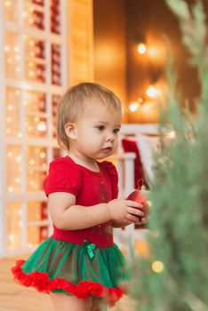 Beautiful baby in new Year costume standing near the christmas tree.