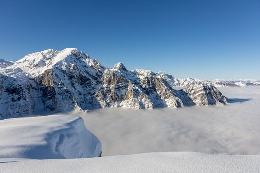 Winter mountains covered with snow landscape over clouds. High quality photo