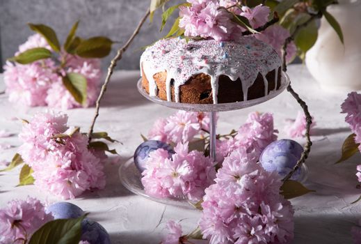 beautiful Easter cake on the table, and colored eggs, homemade cakes, still life with a silver teapot on a background of pink sakura. High quality photo