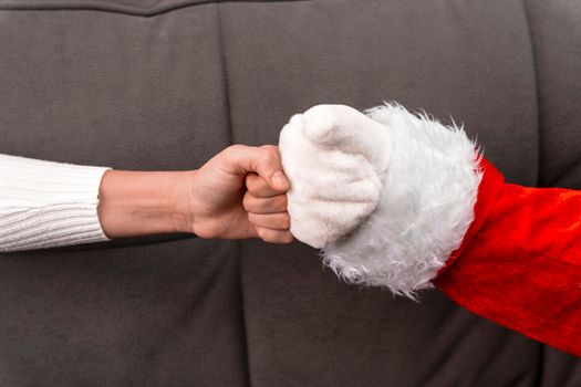 Santa's hand and the girl's hand bump fists. New Year's greetings. Christmas holiday greeting. A gesture from Santa