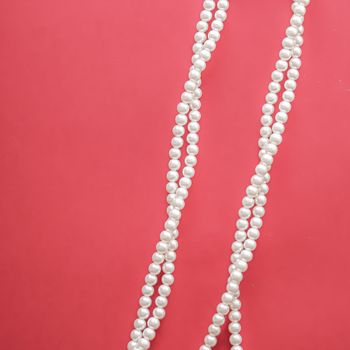 Pearl jewellery necklace on coral background.