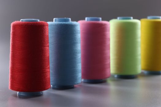 Multicolored thread spools on gray background. Set of colored threads concept