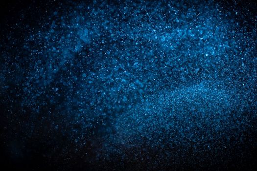 Abstract real blue dust particles on black background. Glittering sparkling bokeh overlay design with copy space for text. High quality photo