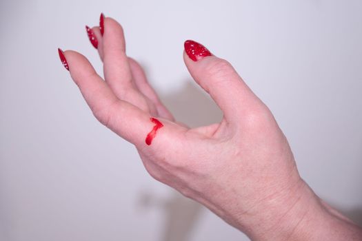 woman cut her hand with paper and gift wrapping red blood on her hand. High quality photo