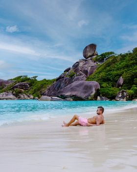 young men laying down on the beach at the tropical Similan Islands in Southern Thailand. guy tanning on the beach