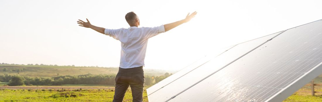 oung engineer is checking an operation of sun and cleanliness of photovoltaic solar panels on a sunset. Concept: renewable energy, technology, electricity, service, green, future.