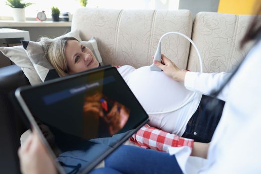 Gynecologist conducts ultrasound of pregnant woman at home. Examination of fetus of child concept