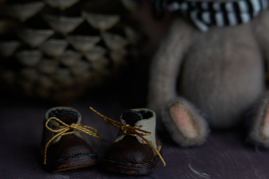 leather small shoes near the feets of teddy bear. the concept of light industry for the manufacture of stylish fashionable shoes for children with small feet and their parents. High quality photo