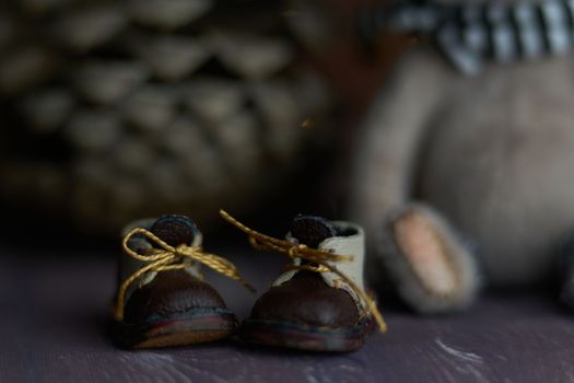 leather small shoes near the feets of teddy bear. the concept of light industry for the manufacture of stylish fashionable shoes for children with small feet and their parents. High quality photo