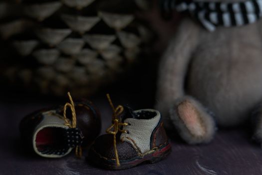 leather small shoes near the feets of teddy bear. the concept of light industry for the manufacture of stylish fashionable shoes for children with small feet and their parents. High quality photo