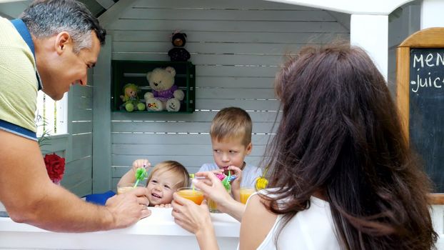 summer, in the garden, parents, mom and dad, carry freshly squeezed fruit juice to treat their children. The family spends their leisure time together. High quality photo