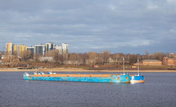 River port. Port cranes on the bank of the river. Embankment of the river port, a barge at the quay wall. Large port cranes on the river. Extraction and transportation of sand other cargo