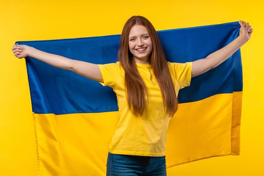 Happy woman with national Ukrainian flag on yellow. Ukraine, patriot, victory in war celebration, banner, Independence day. High quality photo