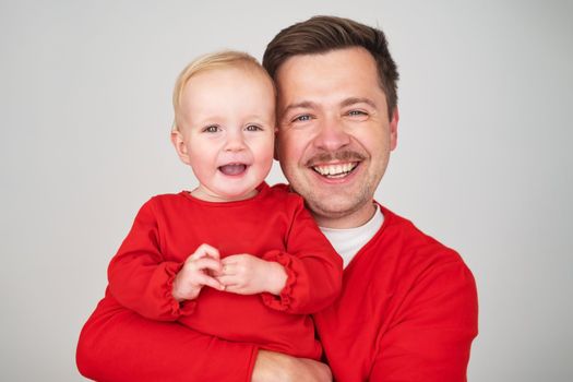 happy father holding his baby daughter smiling at camera. Studio shot