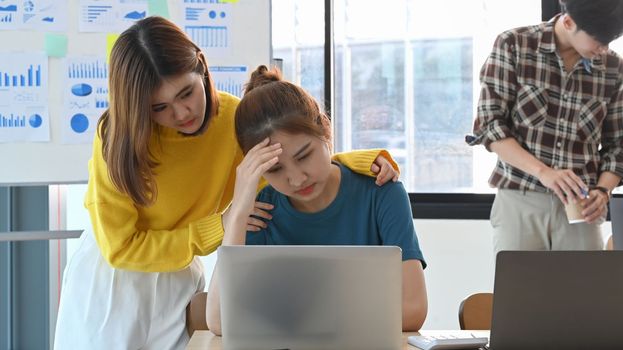 Asian woman embracing, comforting stressed frustrated female coworker. Problems, friendship and care concept.