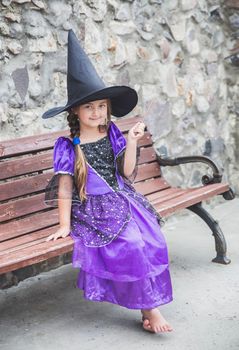 charming young sorceress sitting with a magic wand on a bench.