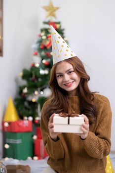 Merry Christmas and Happy Holidays Young woman with a beautiful face in a yellow shirt shows joy with gift boxes in a house