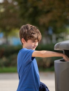 Caucasian kid 9 year old try to throw trash in public trashcan. Concept of garbage, Recycle environment, save world