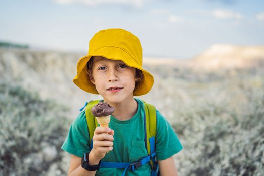 Boy tourist boy eating turkish ice cream while exploring valley with rock formations and fairy caves near Goreme in Cappadocia Turkey.