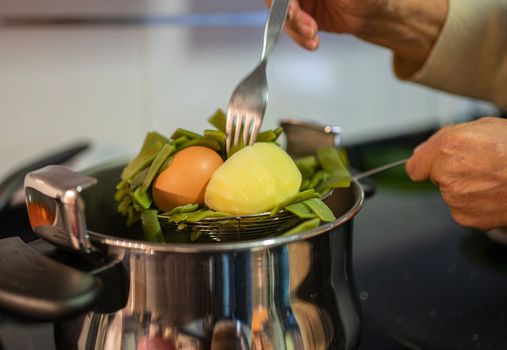 mature aged woman hands taking out ready to eat healthy and cheap food from cooking pot