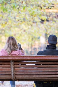 Young couple relaxing on park bench together on a sunny day