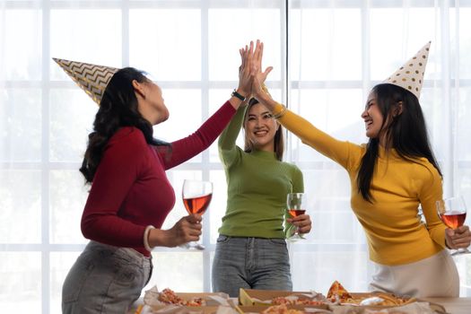 Group of happy young Asian people with friends celebrating clinking glasses during dinner party.