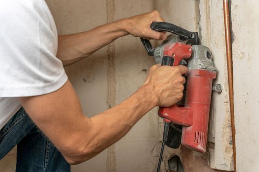 professional construction power tool for cutting strob in the hands of a worker during the renovation of the apartment. A hand-held power tool with two diamond discs for cutting grooves in the wall for laying electrics. Professional tool. Close-up