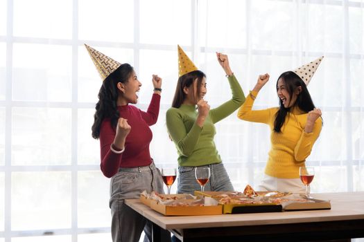 Group of happy young Asian people with friends celebrating clinking glasses during dinner party.