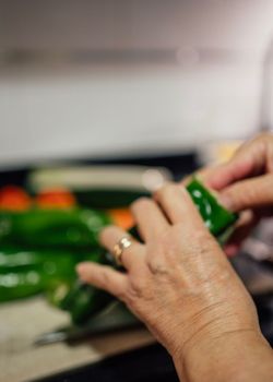 Woman Hand with ring cutting and cleaning green pepper from its seeds.