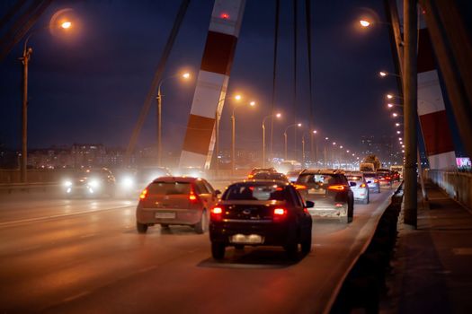 29.11.2022, Cherepovets, Russia. A large automobile bridge on which cars drive at night. A bridge with large columns and lighting. Cars are driving over the bridge