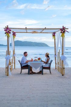 Romantic dinner on the beach in Phuket Thailand, couple man and woman mid age Asian woman and European man having dinner on the beach in Thailand during sunset.