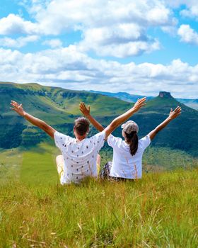 couple men and women with hands up in the mountains of Drakensberg Giant Castle South Africa , during a hiking trip in the mountains at summer