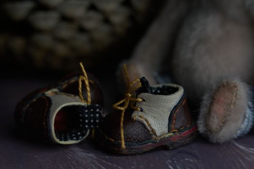 leather small shoes near the feets of teddy bear. the concept of light industry for the manufacture of stylish fashionable shoes for children with small feet and their parents. High quality photo