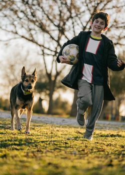 Kid with ball running from dog playing catch-up game.