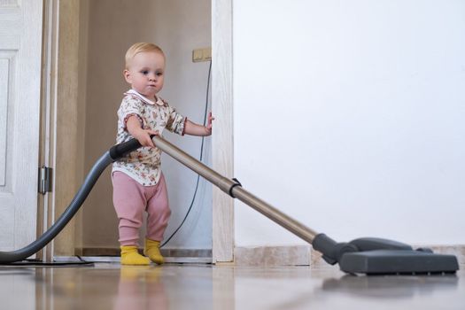 Baby boy cleaning the carpet with vacuum cleaner. High quality photo