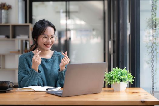 Beautiful women student studying online takes notes on her laptop to gather information about her work smiling face and a happy study posture