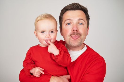 happy father holding his baby daughter smiling at camera. Studio shot